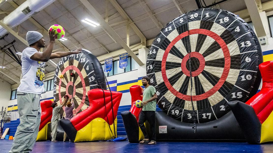 Students participating in a large game using an inflatable dart board and a soccer ball.