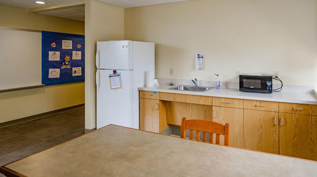 A shared dorm kitchenette with a sink, refrigerator and microwave.