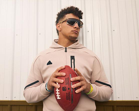 Patrick Mahomes, holding a football, looks to his left wearing sunglasses. 