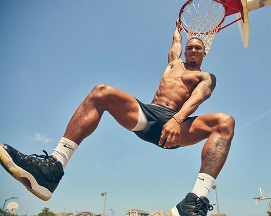 Nate Pierre-Louis hangs from basketball hoop.