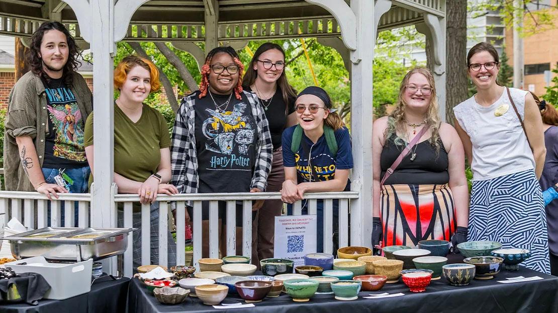 A group of students pose for a photo at the "Empty Bowl Project" event.