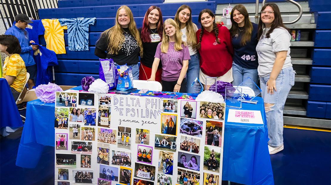Students who are members of Delta Phi Epsilon pose for a photo at an involvement fair event. 