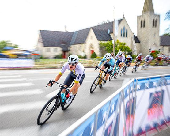 Action shot of bicyclists rounding a corner on a street during a race.