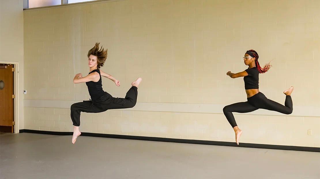 Two dancers practicing leaps.