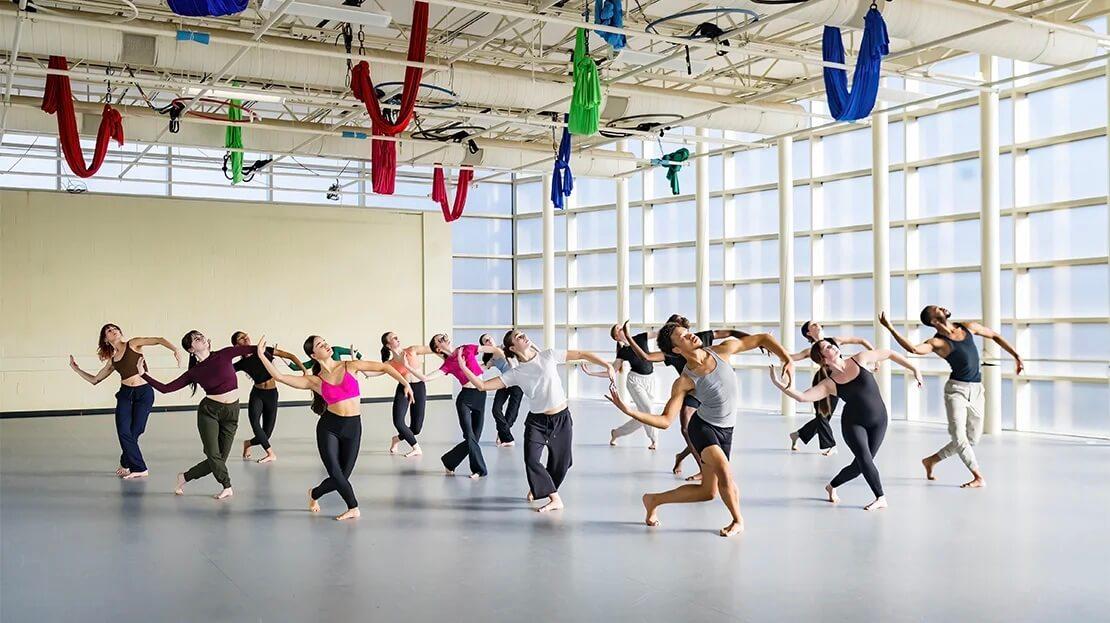 A large group of dancers practicing in a dance studio.