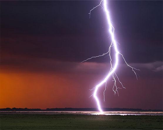 A lightning bolt hitting the water through a dark sky,