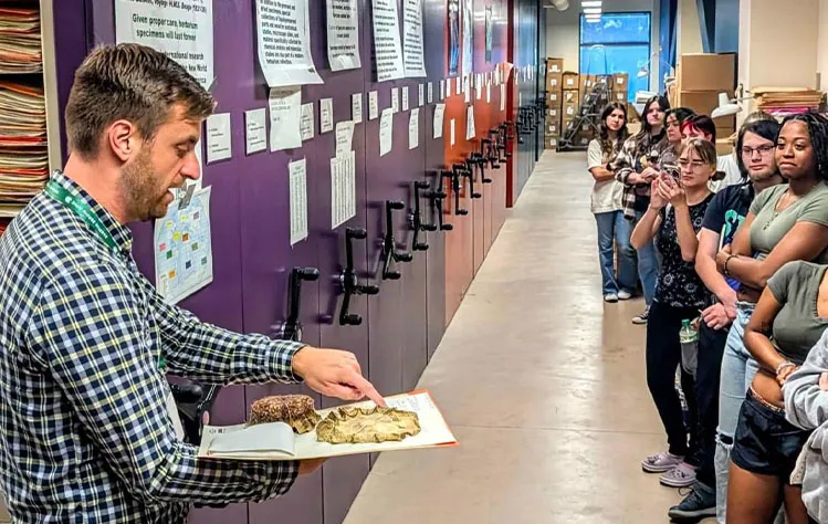 Professor displaying plants to students at the botanical garden.