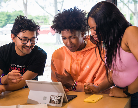 Three students working together at a laptop. 