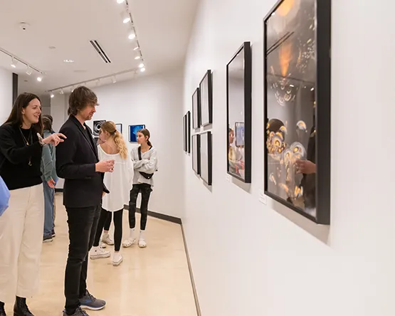 Kooyumjian Gallery visitors viewing framed photographs displayed along a curved white gallery wall.