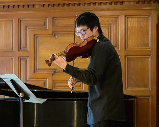 A student performs on the violin in a recital.