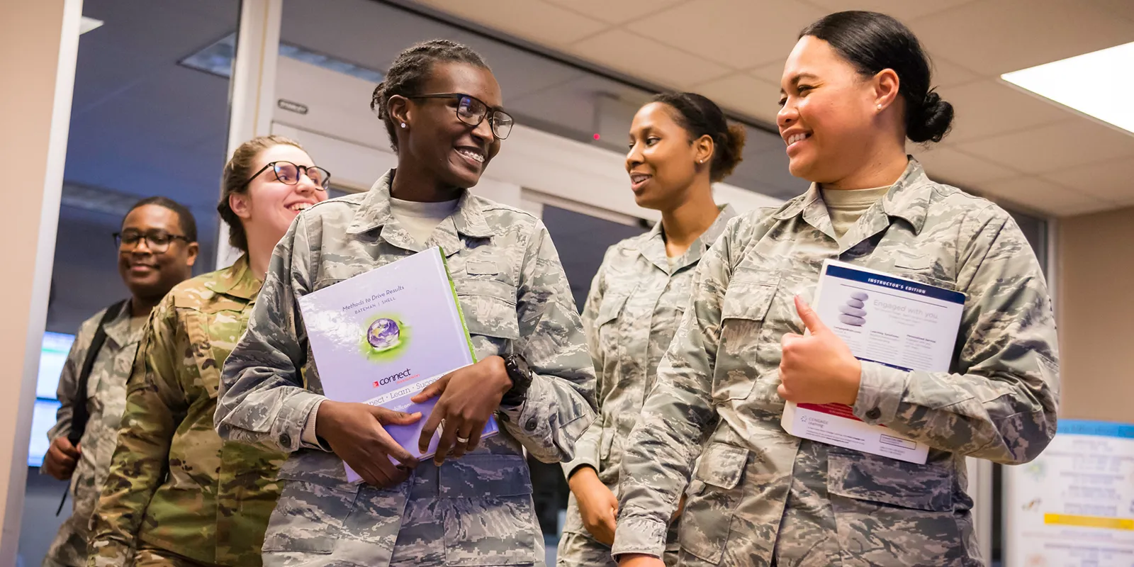 Four Webster military students walking down campus hallway.