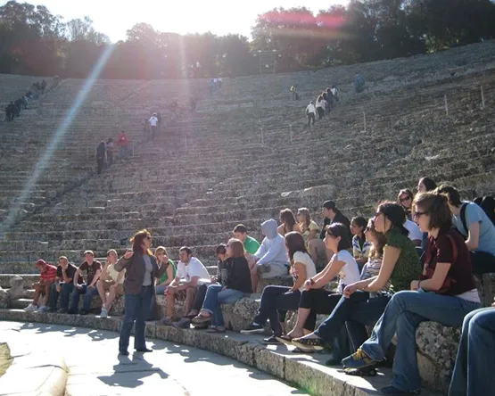 Students gather in ancient Greek coliseum and listen to professor lecturing